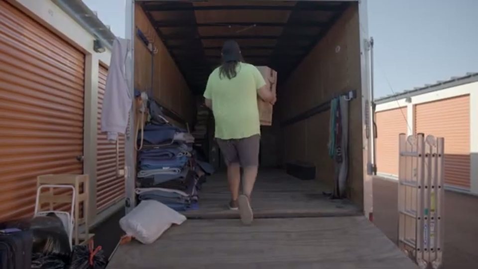 three men moving a home gym machine on a suburban driveway, face visible