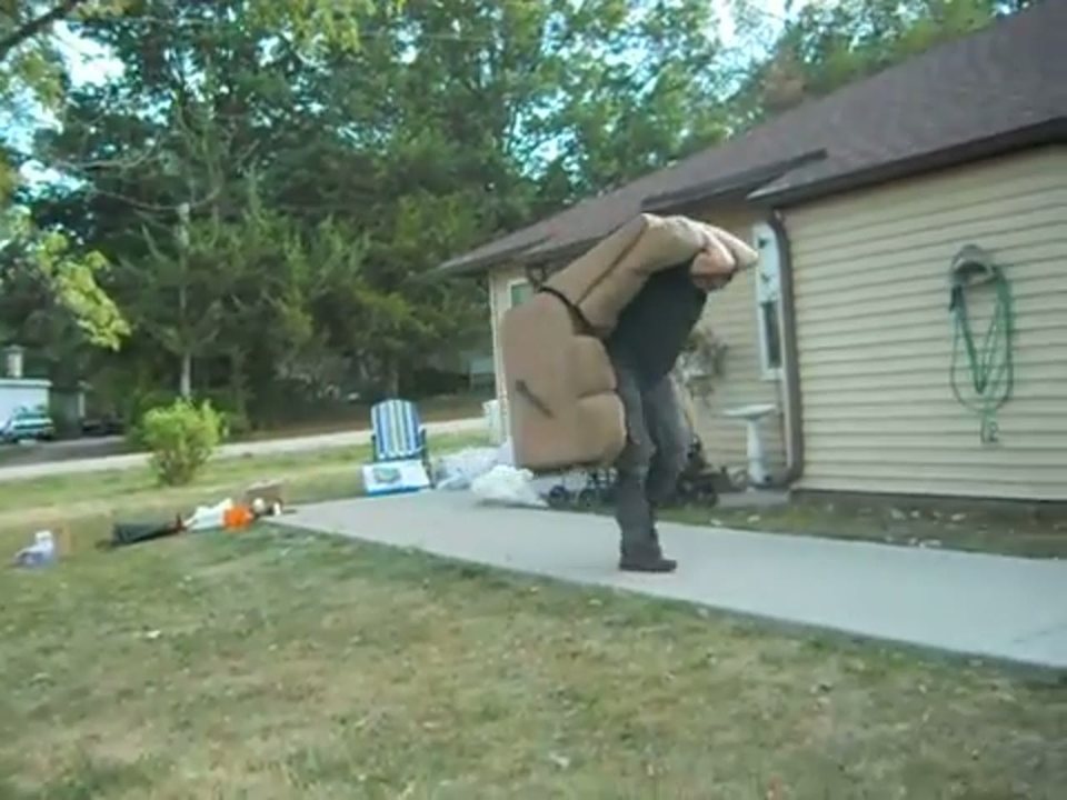 a mover carrying a sofa across the front lawn to a San Antonio home